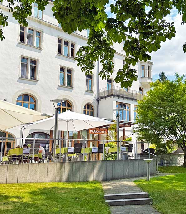 Das Bild zeigt die Außenterrasse eines Parkhotels an einem sonnigen Tag.